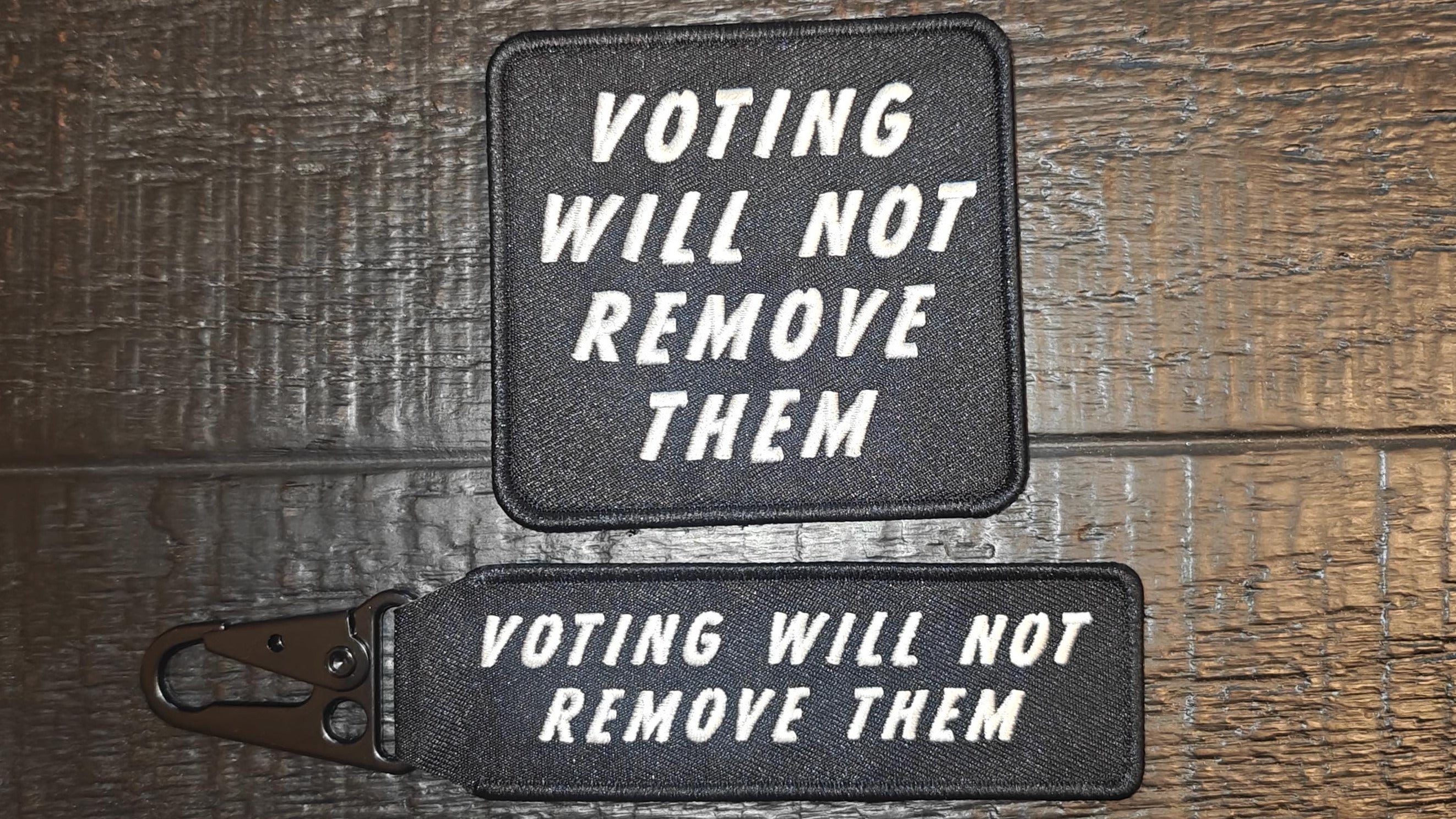 Two patches with 'Voting will not remove them' text on a wooden surface